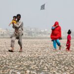 A woman covers her face with scarf to avoid heat while walking with her family along the beach on a hot summer day in Karachi, Pakistan, May 20, 2016. REUTERS/Akhtar Soomro TPX IMAGES OF THE DAY